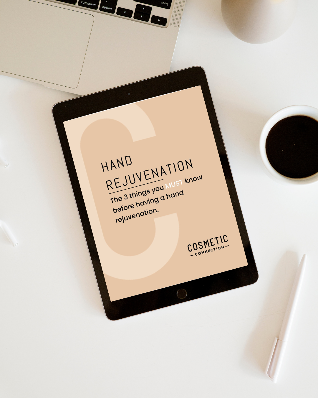 A tablet displaying a page titled Hand Rejuvenation: The 3 things you MUST know before having a hand rejuvenation sits on a white desk next to a coffee cup and part of a laptop.