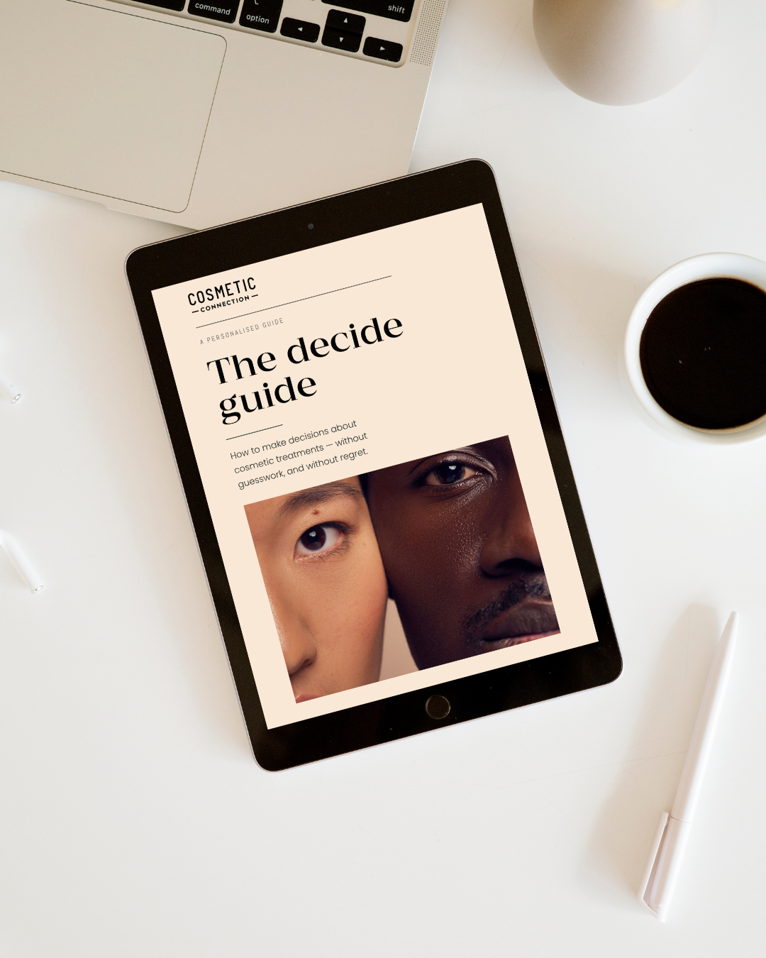 A tablet displays a guide titled The decide guide showing a close-up of two diverse faces; nearby are a laptop, coffee cup, and pen on a cream-colored desk.